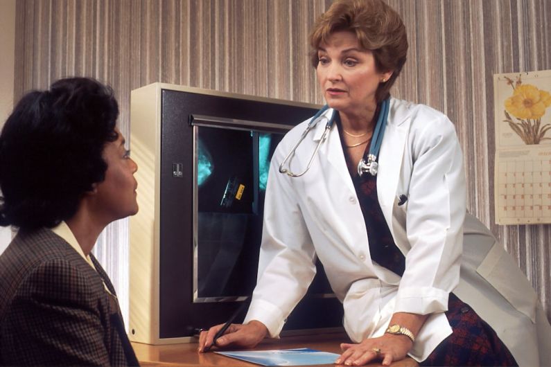 Tenant Screening - doctor sitting on desk talking to sitting woman