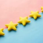 Reviews Ratings - a row of yellow stars sitting on top of a blue and pink surface