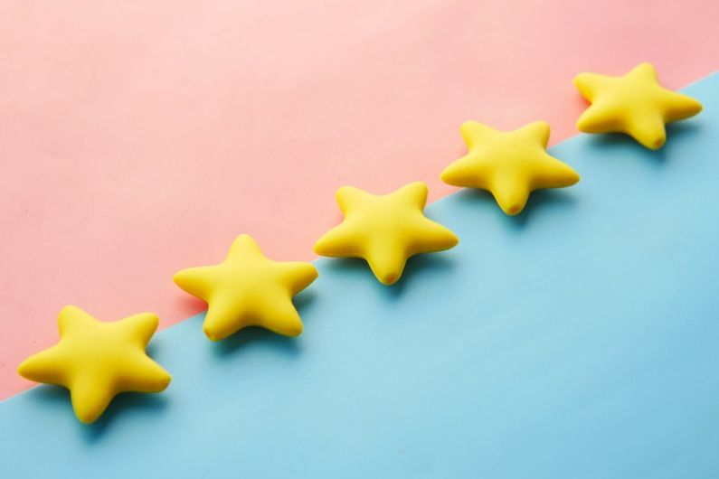 Reviews Ratings - a row of yellow stars sitting on top of a blue and pink surface