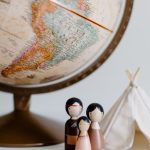 International Home - From above of miniature toys tipi house and American Indian family placed near vintage globe against gray background at daytime