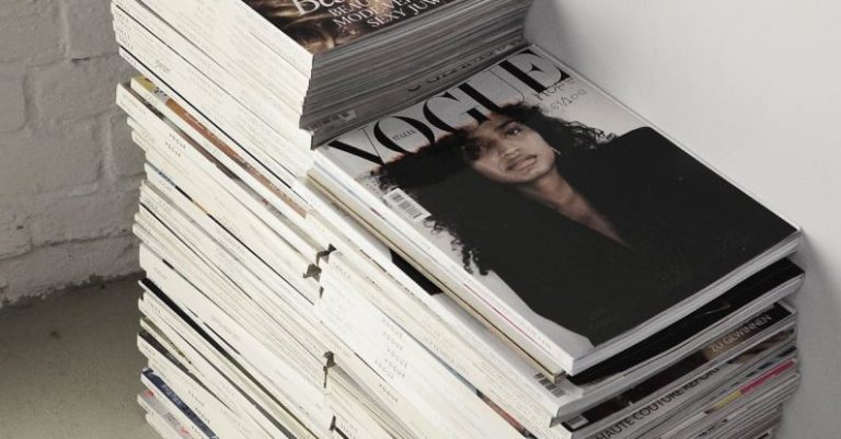 Commercial Trend - High angle many fashion magazines stacked on floor against white brick wall in studio