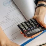 Foreign Management - Person Holding Black Calculator While Using Laptop