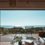 Offshore Property - Interior design of luxurious apartment with large balcony doors and wooden terrace having picturesque view on green forested seashore and calm blue sea