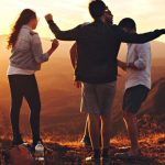 Millennials Group - Four Person Standing at Top of Grassy Mountain