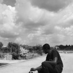Curb Appeal - A man kneeling on the ground with his skateboard