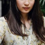 Newsletter - Young attentive Asian woman messaging on mobile phone in street cafe