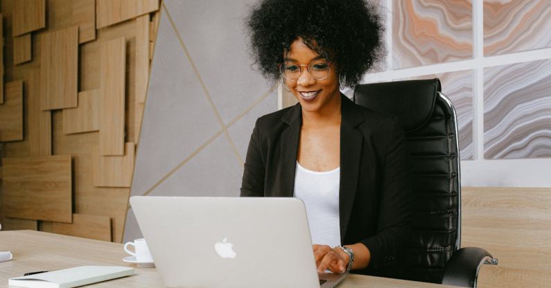 Webinar - Woman in Black Blazer Sitting by the Table While Using Macbook