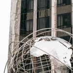 Globe Finance - Landmark sculpture Columbus Circle globe installed outside modern skyscraper in Manhattan New York City