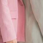 Future Trend - Side view of crop anonymous female models wearing similar trendy suits standing together against gray background