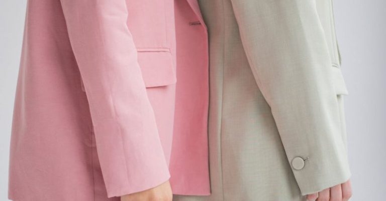 Future Trend - Side view of crop anonymous female models wearing similar trendy suits standing together against gray background