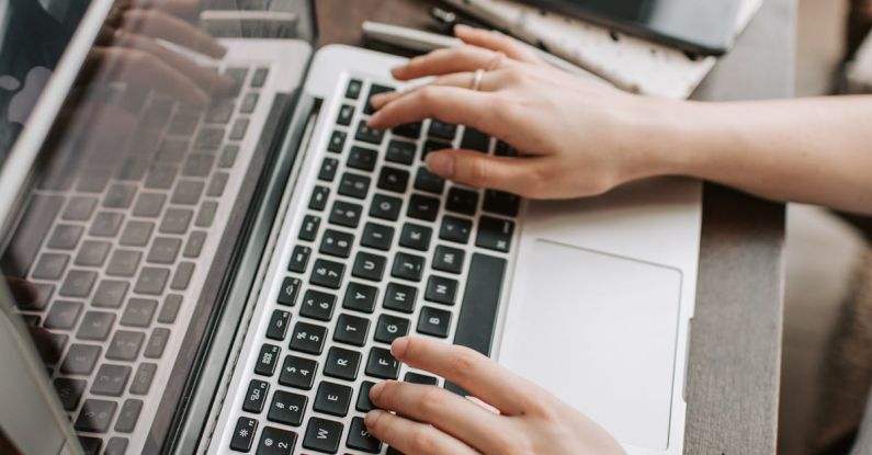 Property Search - From above of unrecognizable woman sitting at table and typing on keyboard of computer during remote work in modern workspace