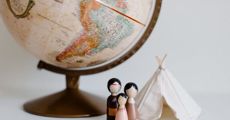 International Home - From above of miniature toys tipi house and American Indian family placed near vintage globe against gray background at daytime