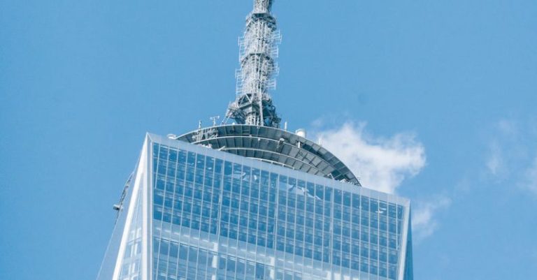 World Investment - Low angle of modern high One World Trade Center with high telecommunication tower in Manhattan