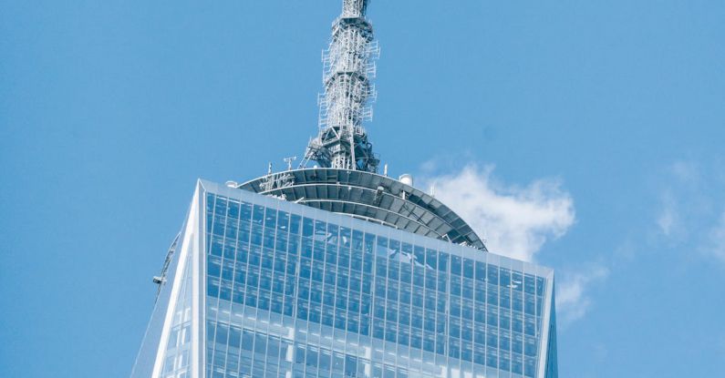 World Investment - Low angle of modern high One World Trade Center with high telecommunication tower in Manhattan