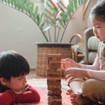 Eco-friendly Build - Content Asian children building wooden tower on floor at home