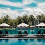 Luxury Villa - Black Outdoor Lounge Chair in Between Blue Swimming Pool Under White Cloudy Blue Sky