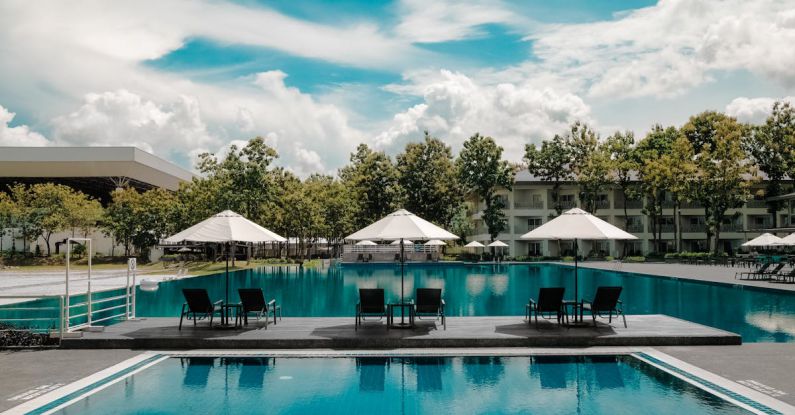 Luxury Villa - Black Outdoor Lounge Chair in Between Blue Swimming Pool Under White Cloudy Blue Sky