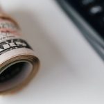 Electronic Signature - From above closeup of plastic calculator with number symbols on buttons near roll of American paper money tied with rubber band
